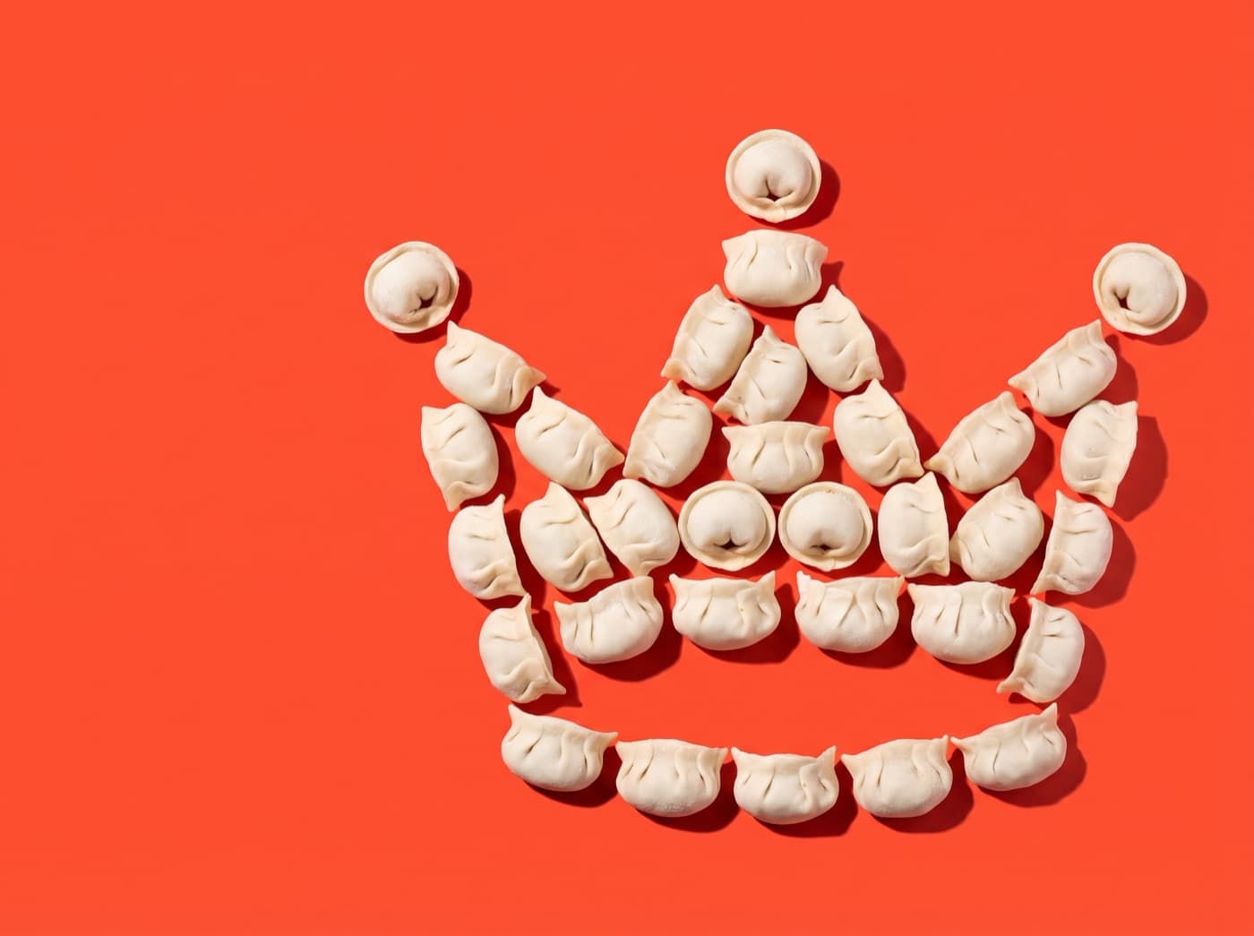 A crown made of pelmeni on a tomato background